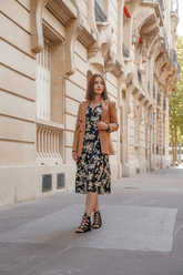 a lady in a black floral printed dress and a brown blazer
